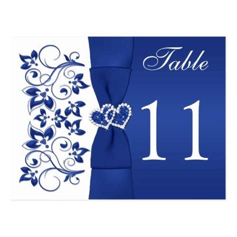 A Table Number Card With Blue Flowers And Leaves On It In The Shape Of