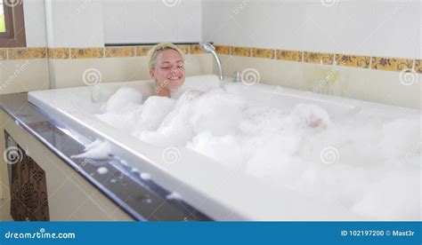 Bathing Young Woman Relaxing In Bath Full Of Foam Raising Legs Smiling