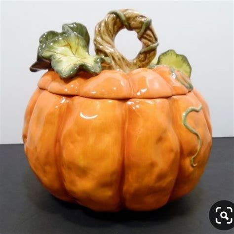 An Orange Ceramic Pumpkin Container Sitting On Top Of A Black Table