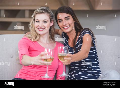 Two Beautiful Women Showing Their Glass Of Wine In The Living Room