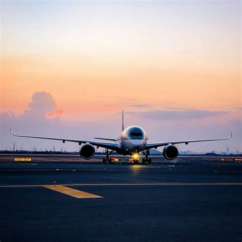 An Airplane That Is Sitting On The Runway At Sunset Or Dawn With Its