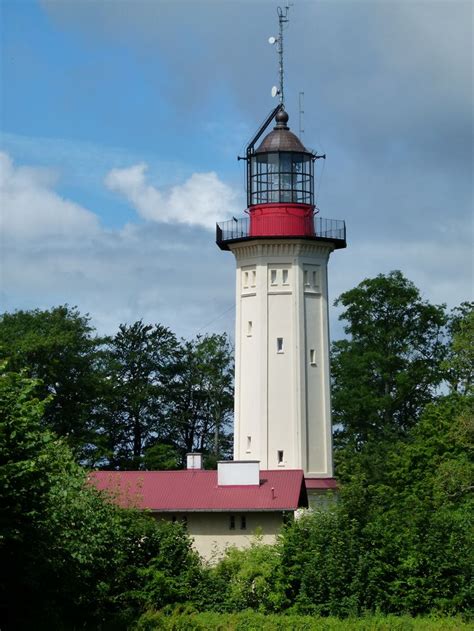 A Red And White Light House Surrounded By Trees