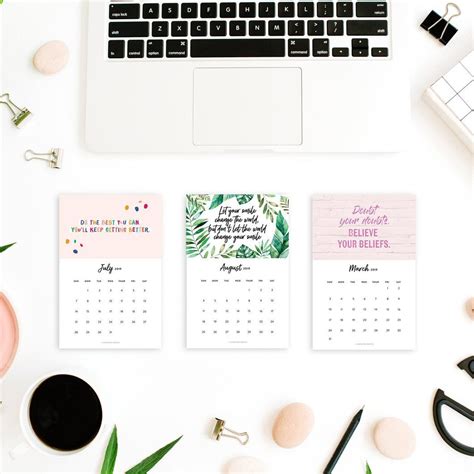 three calendars sitting on top of a desk next to a laptop and other ...