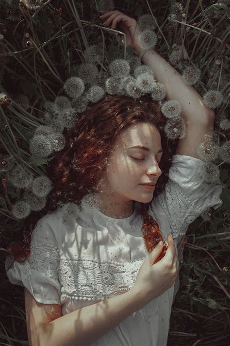 A Woman Is Laying In The Grass With Her Hands Behind Her Head