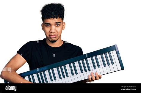 Young african american man holding piano keyboard depressed and worry ...