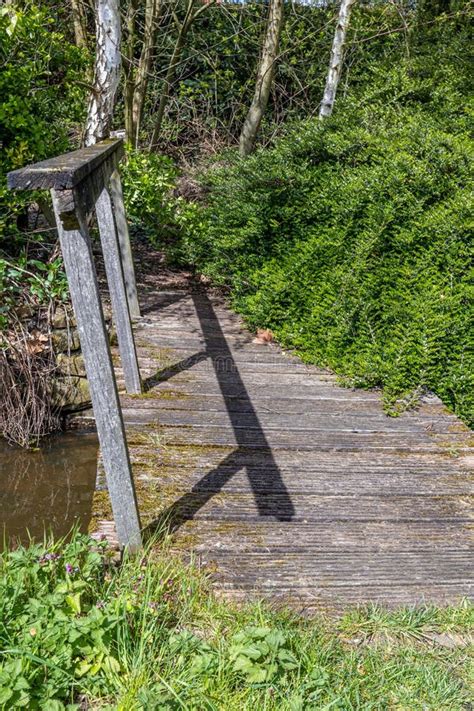 Old And Worn Small Simple Wooden Bridge Over A Stream And Sloping Fence