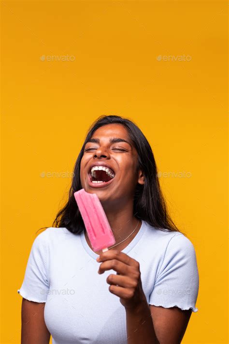 Indian Woman Laughing Eating Pink Popsicle On Yellow Background Asian