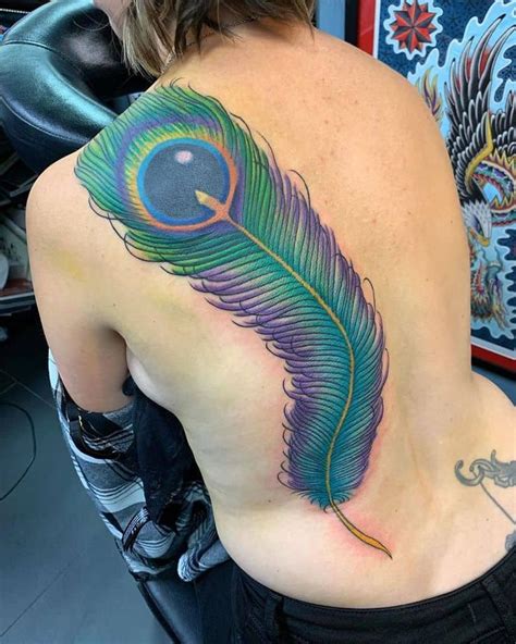 A Woman S Back With A Colorful Peacock Feather Tattoo On Her Left Side