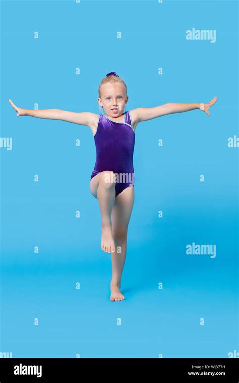 Portrait Of A Young Female Gymnast Performing Over Blue Background