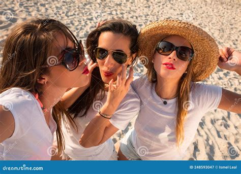 Three Girls Laughing And Enjoying Themselves In The Sand Of A Tropical Beach At Sunset Stock