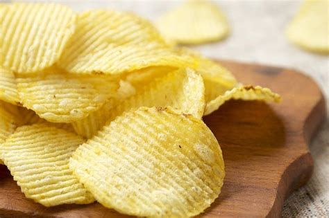 Salted Wavy Potato Chips On A Rustic Wooden Board Low Angle View