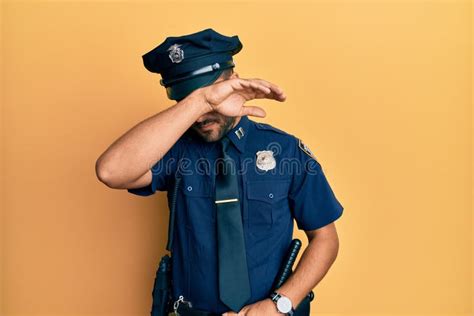 Handsome Hispanic Man Wearing Police Uniform Covering Eyes With Arm