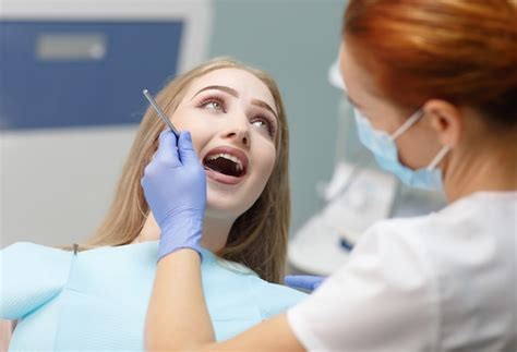 Dentista Feminina Verificando Os Dentes Do Paciente Foto Premium