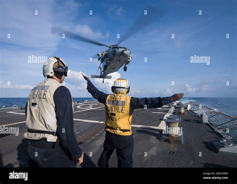 Boatswain S Mate Signals To An MH 60S Sea Hawk Helicopter As It Takes