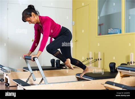 Sporty Adult Latina Doing Stretching Exercises On Pilates Reformer Stock Photo Alamy