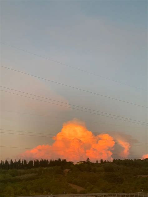 an orange cloud is in the sky above some trees