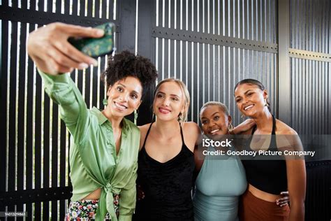 Smiling Female Friends Taking Selfies Together During A House Party