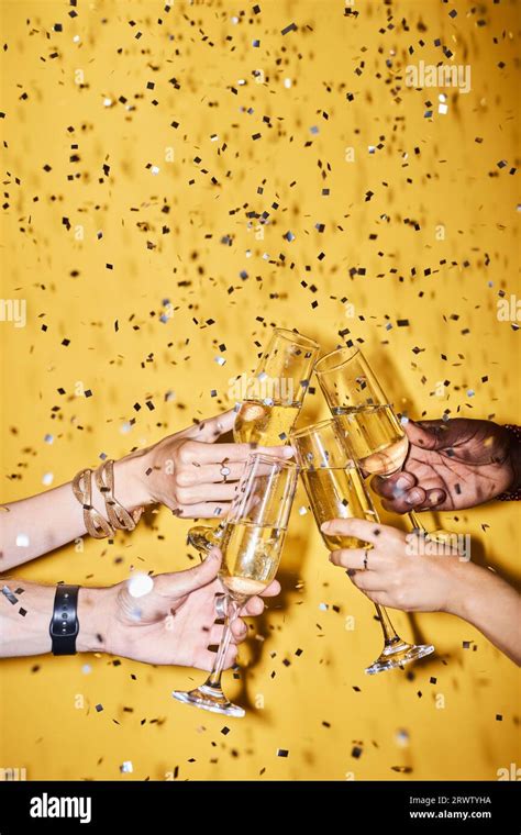 Closeup Of Group Of People Clinking Champagne Glasses Against Vibrant Yellow Background With