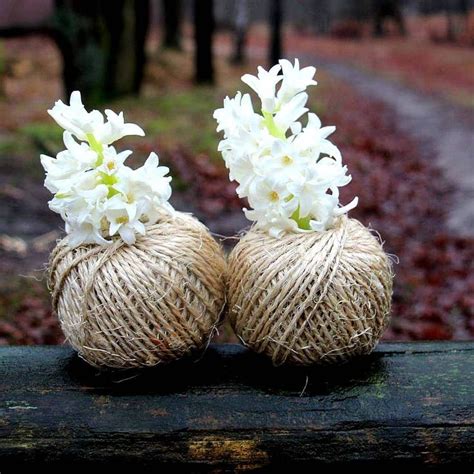 Two Balls Of Twine With White Flowers Are Sitting On A Wooden Bench In