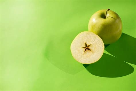 Premium Photo Green Apple Whole And Cut Half On A Green Background