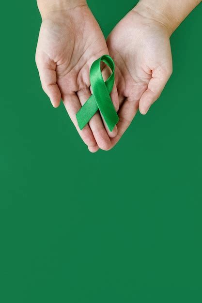 Premium Photo Adult Hands Holds Green Ribbon On Green Background