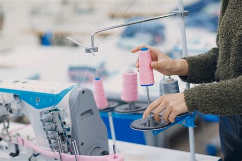 Costurera hermosa joven cose en la máquina de coser en la fábrica