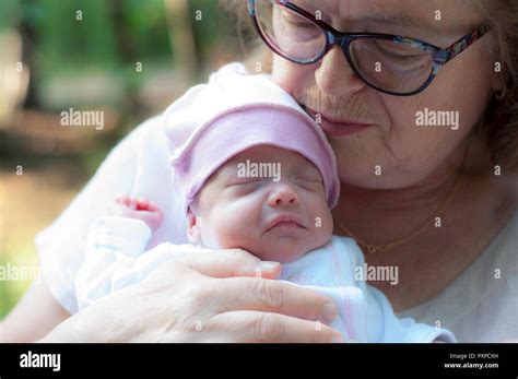 Grandmother Holds A Small Newborn Granddaughter In Her Arms Stock Photo