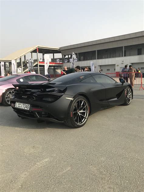 A matte black McLaren 720S with red inscription on the tires at a car ...