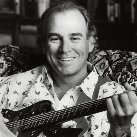 A Black And White Photo Of A Smiling Man Holding An Electric Guitar In