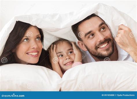 Familia Feliz Que Miente En Cama Debajo De La Manta En Casa Foto De