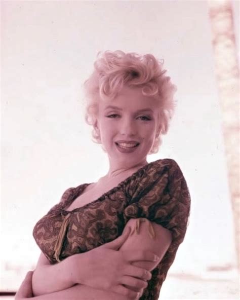 an old photo of a woman with short blonde hair smiling at the camera and wearing a brown dress