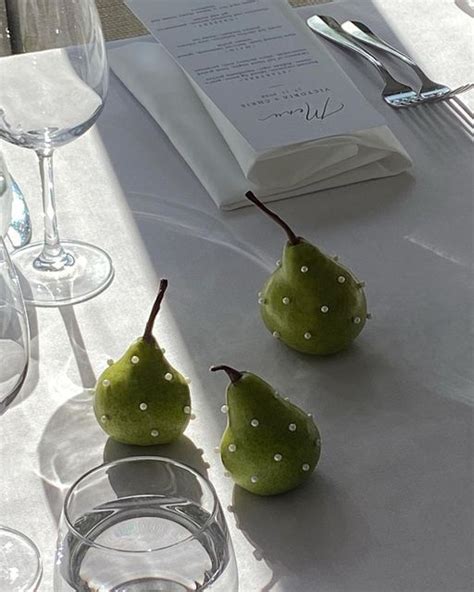 Three Pears Sitting On A Table With Wine Glasses And Silverware Next To