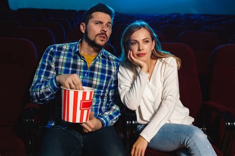 映画館、家または映画館で映画を見ている魅力的な若い白人カップル。表現力豊かで、驚いて、感情的に見えます。一人で座って楽しんでください。関係、愛