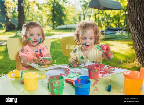 Two Year Old Girls Painting With Poster Paintings Together Against