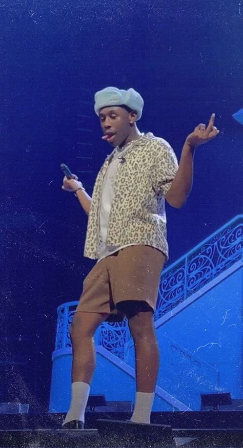 A Man Standing On Top Of A Stage Holding A Cell Phone In His Right Hand