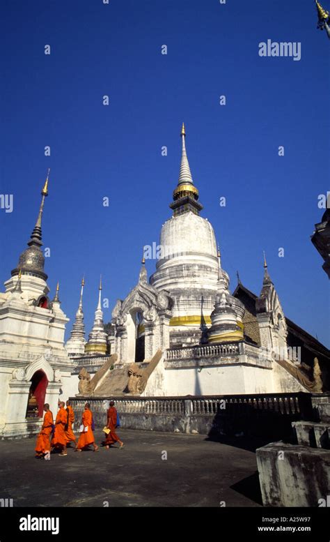 Buddhist Monks Walks By A Group Of Pantheons In Wat Suan Dok In Chiang