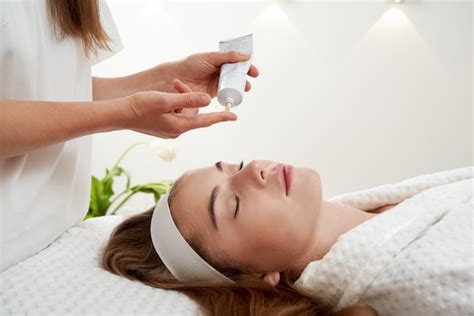 Premium Photo Cosmetologist Applying Cream On Female Face Woman