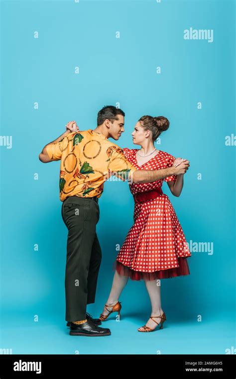 Stylish Dancers Holding Hands While Dancing Boogie Woogie On Blue