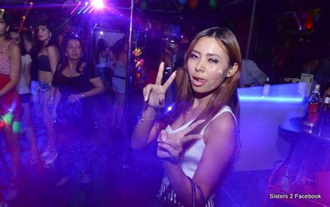 a woman standing in front of a group of people at a party with one hand up