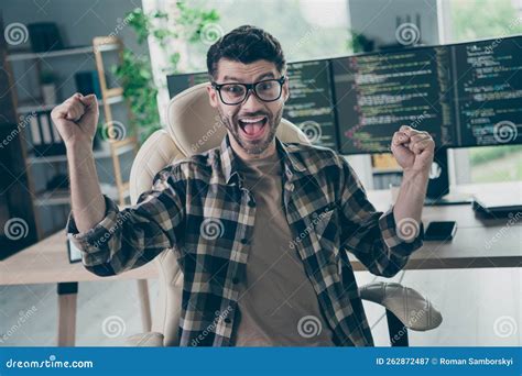 Portrait Of Delighted Overjoyed Person Sit Chair Raise Fists Shout Yes