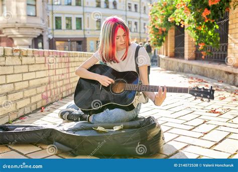 Creative Female Playing Acoustic Guitar Sitting On Sidewalk With Guitar Case And Cash Stock