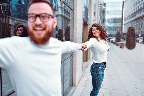 Happy Couple Holding Hands While Enjoying Walking In Empty City