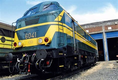 A Blue And Yellow Train Is Parked Next To Another Train On The Tracks