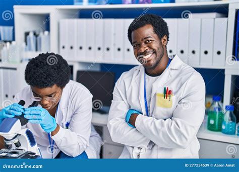 African American Man And Woman Scientists Using Microscope At