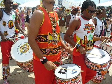 a group of men in red and white outfits playing drums with other people ...