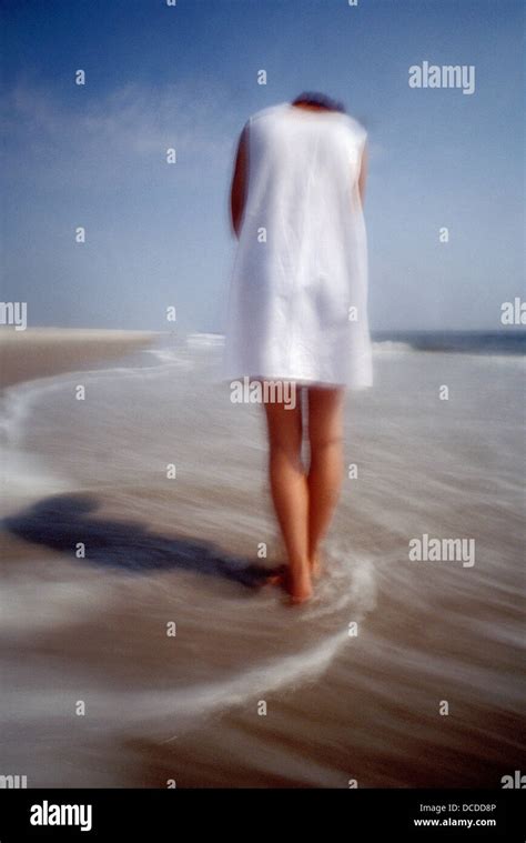 Lone Woman Walking Along Seashore Stock Photo Alamy