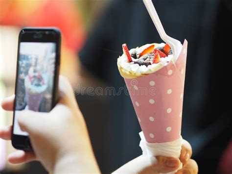 As Mulheres Que Guardam Um Telefone Celular Tomam A Foto De Bolos Dos