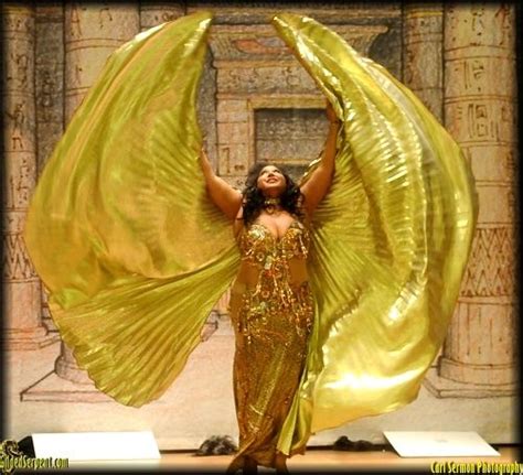 A Woman In A Gold Dress With Her Arms Outstretched