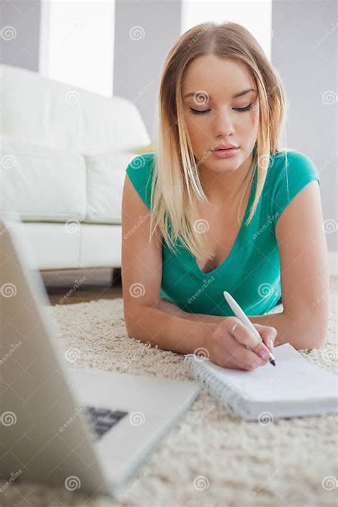 Concentrating Woman Lying On Floor Doing Her Homework Using Laptop