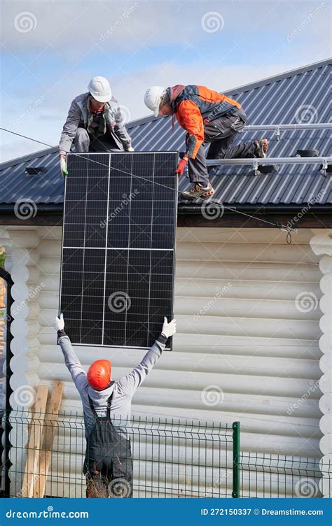 Professional Technicians Lifting Solar Panels On A Roof Of House Stock